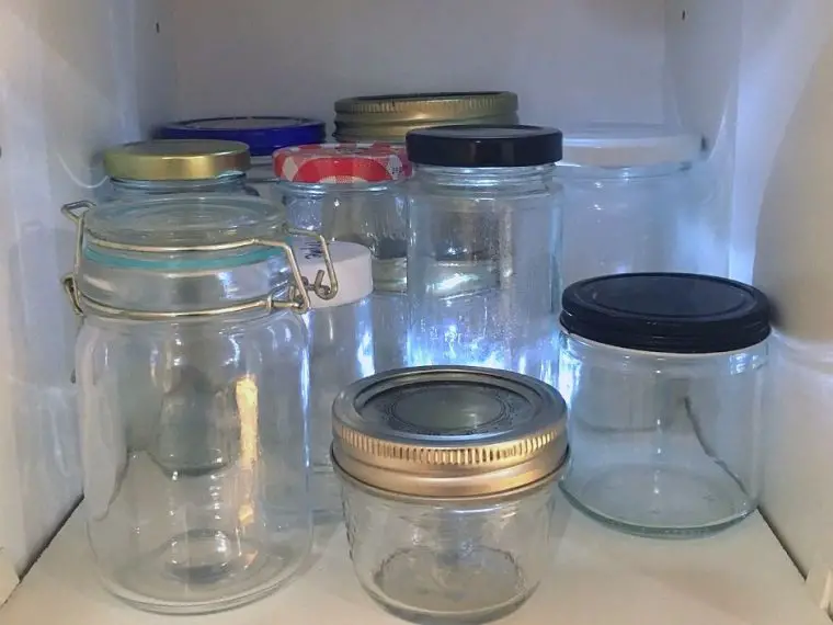 Shelf of jars showing how to remove labels from jars so you can reuse them.