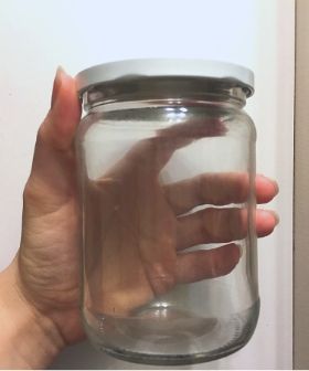 hand holding empty jar. Remove the label from glass jars so you can reuse them