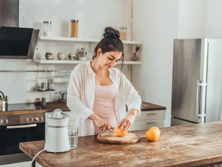 woman teaching frugal kitchen tips and slicing an orange