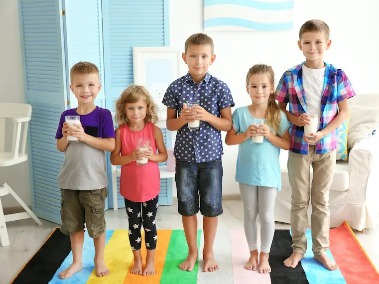 5 siblings holding glasses of milk representing how to save money on groceries for a large family