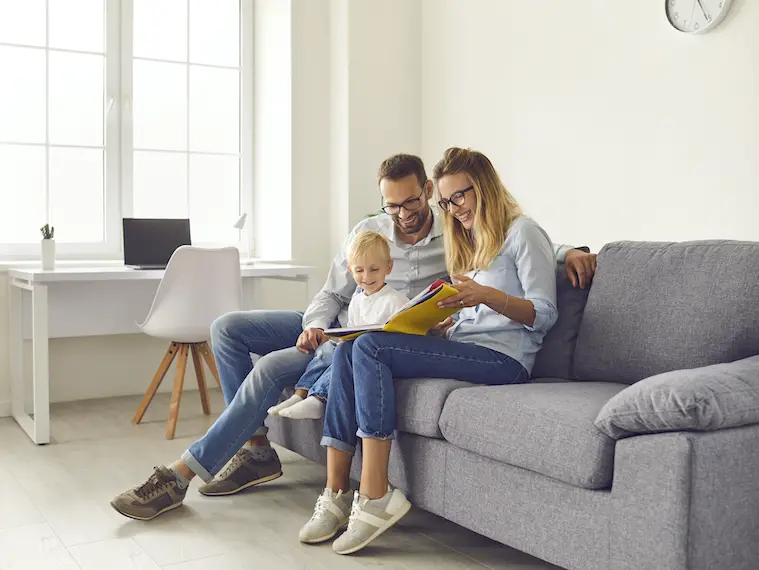 minimalist family parents and kid sitting on sofa, reading book