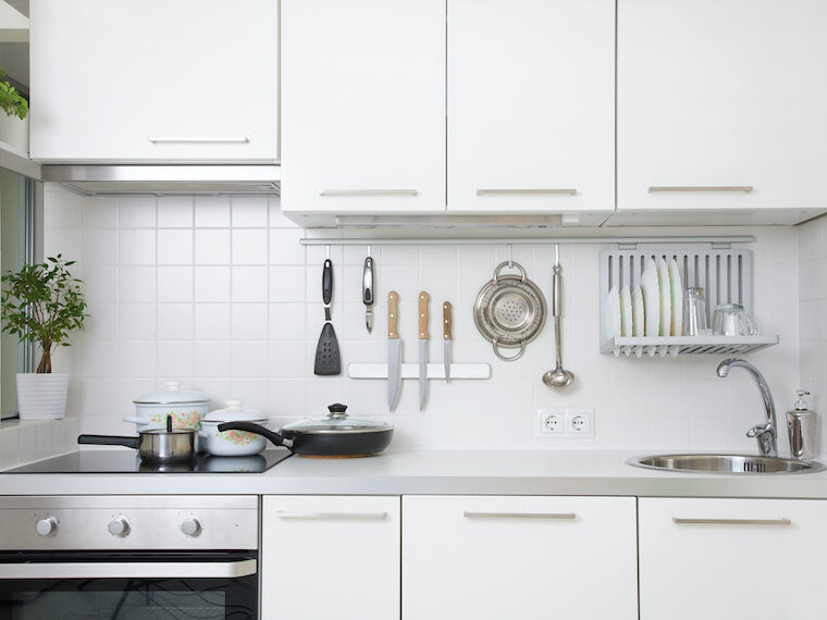 small white kitchen with utensils, knives, dish rack on backsplash is a good example of how to maximize space in a small kitchen