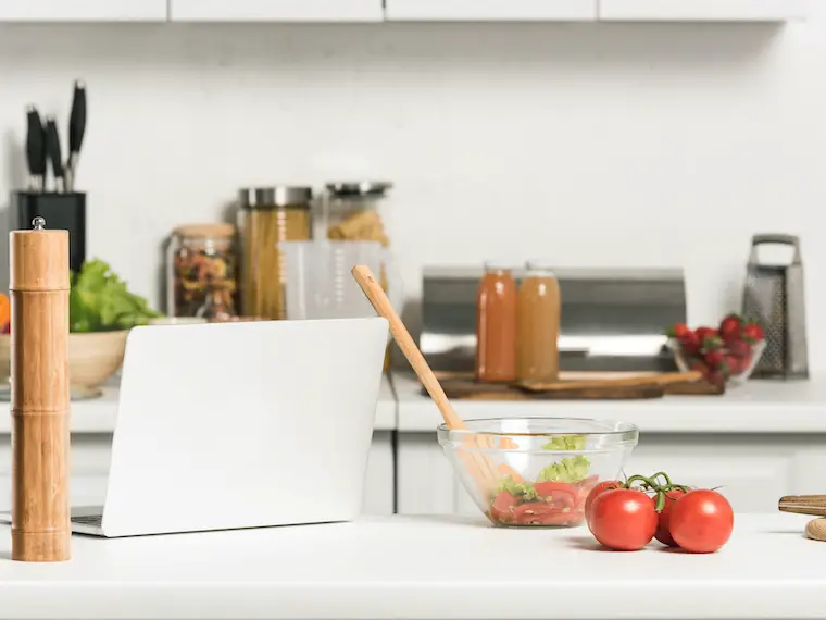 minimalist recipe on laptop with recipe ingredients on white kitchen counter