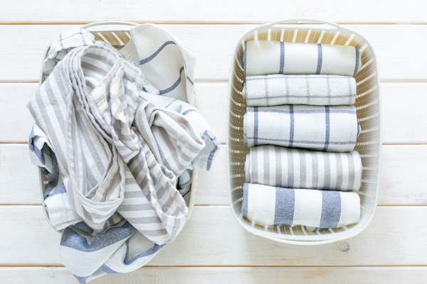 motivate yourself to clean with before and after picture of your mess. Image shows basket of messy unfolded towels. beside it, another basket shows them neatly folded.